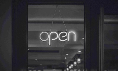 Black and white photo of an LED open sign hanging in a window.